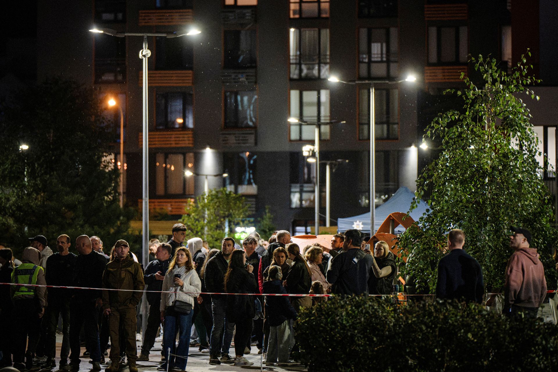 Local residents stand in front of a high-rise residential building damaged following a Russian drone attack in Kyiv, Ukraine, on Oct. 12, 2026