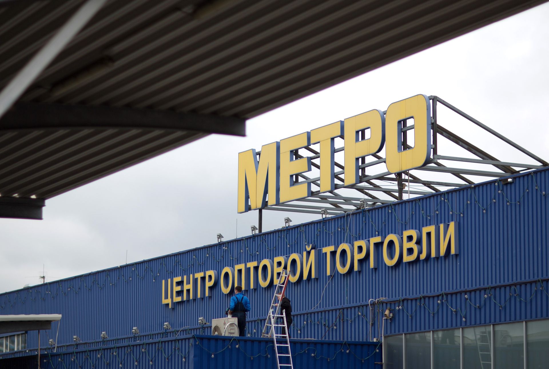 Maintenance workers carry ladders onto the roof of a Metro Cash &amp;amp; Carry store, the Russia unit of Metro AG, in Moscow, Russia, on Aug. 29, 2014. (Andrey Rudakov/Bloomberg via Getty Images)