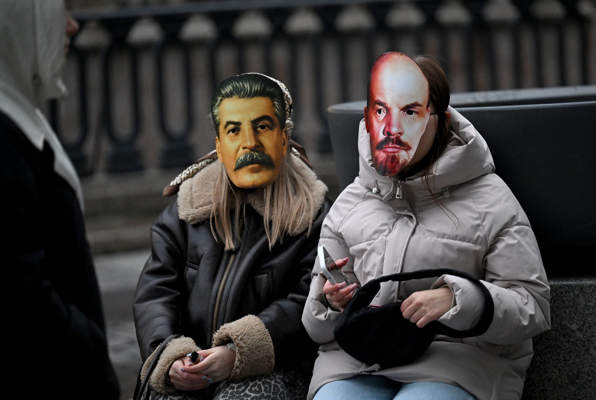 Молоді жінки в масках радянських лідерів Йосипа Сталіна та Володимира Леніна відвідують концерт вуличних музикантів у Санкт-Петербурзі, Росія, 27 жовтня 2025 року.